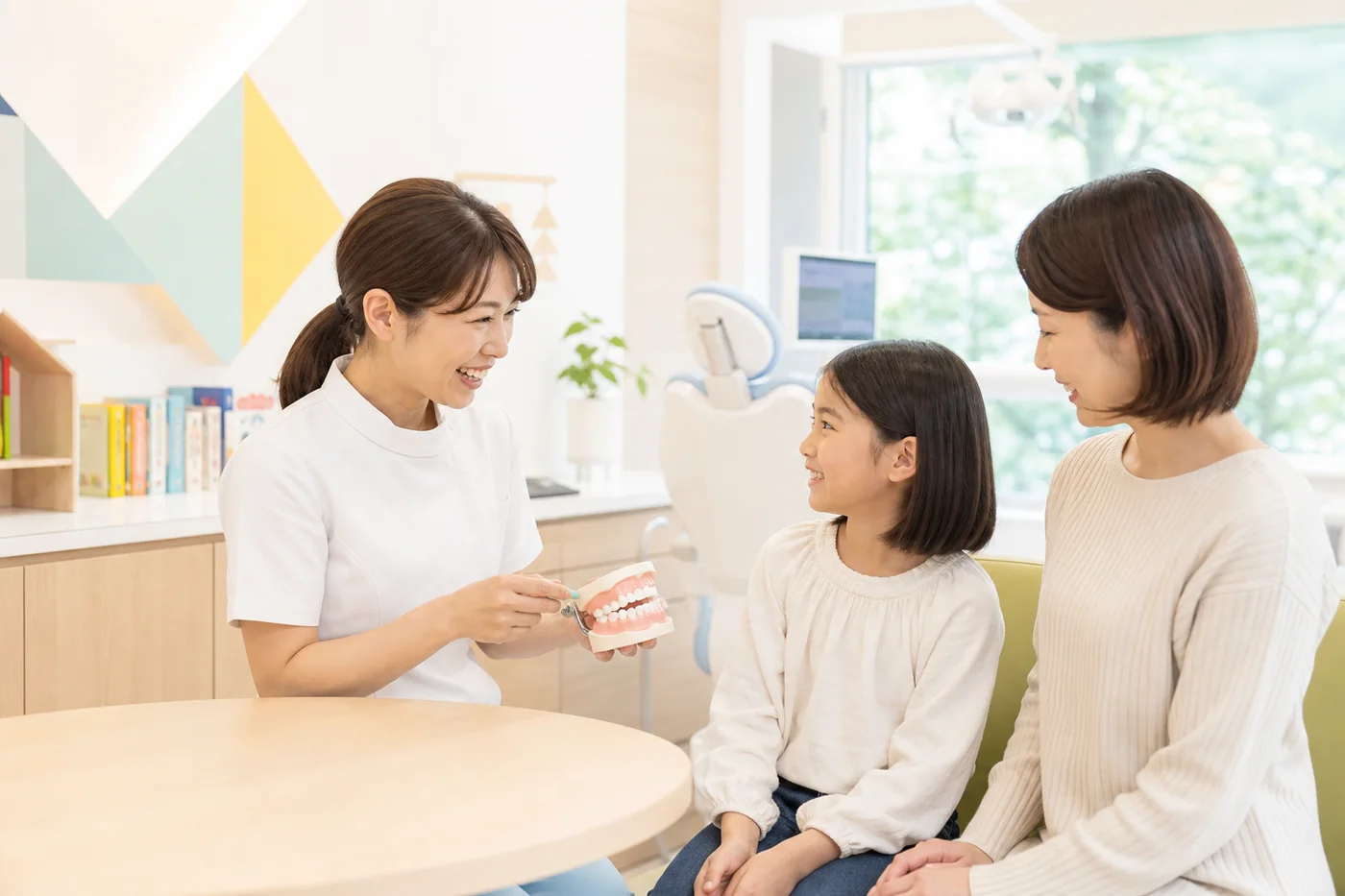 歯科衛生士がお子さんと保護者へ歯の模型を使って説明する様子