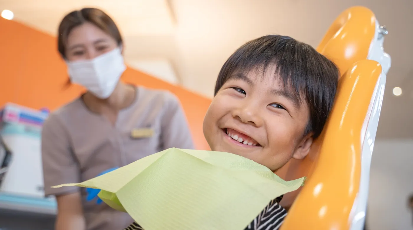 歯科衛生士のそばで笑顔を見せる男の子