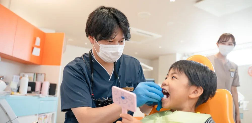 歯科医師が鏡を使って男の子に説明している様子