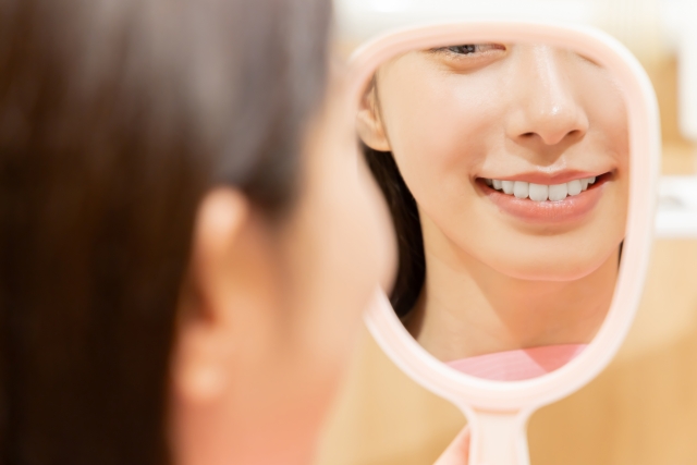 鏡で自身の歯を眺める女性